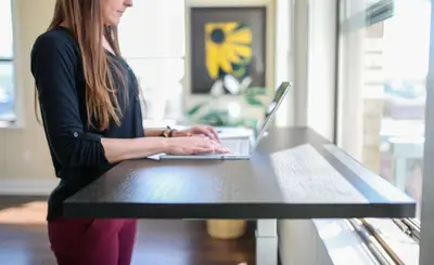 A woman in a black shirt sitting at a table and using a MacBook